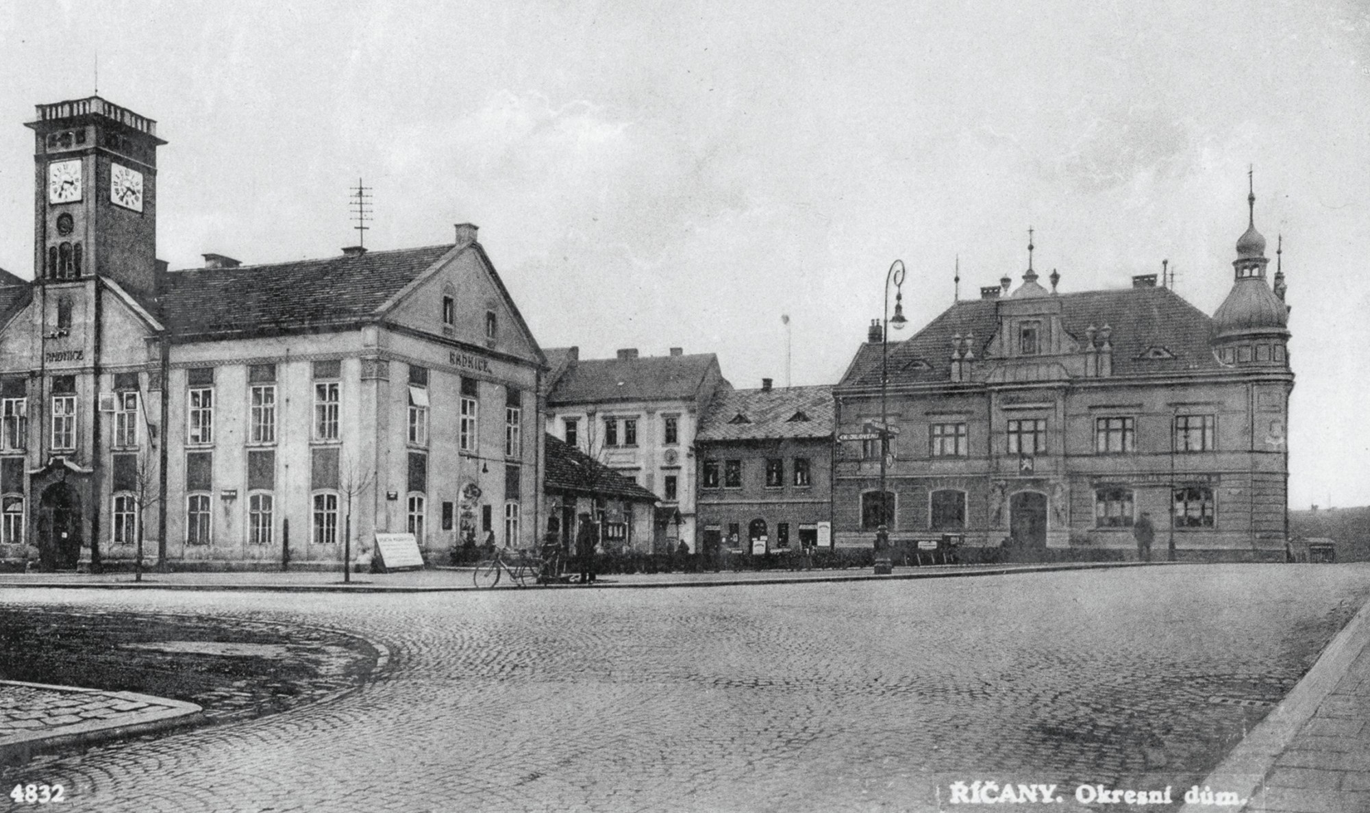 BUDOVA DNEŠNÍ NOVÉ RADNICE VYROSTLA NA SEVERNÍ STRANĚ ŘÍČANSKÉHO NÁMĚSTÍ V ROCE 1913 JAKO „OKRESNÍ DŮM“ – TEHDY TO BYLO SÍDLO OKRESNÍHO ZASTUPITELSTVA. MĚLO TENKRÁT 24 ČLENŮ. BUDOVA (DNES S ČP. 53) VZNIKLA NA MÍSTĚ BÝVALÝCH DOMŮ Č. 54 A 53. DŮM Č. 53 KOUPILO OKRESNÍ ZASTUPITELSTVO PRO SVÉ ÚŘADY UŽ V LISTOPADU 1873. DŮM Č. 54 KOUPIL OKRES V ROCE 1911. DOMY BYLY V ROCE 1911 ZBOURÁNY A ZAČALA SE STAVĚT BUDOVA OKRESNÍHO DOMU. VYSTAVĚL HO STAVITEL HELL ZE SEDLCE, STÁL ASI 120 TISÍC KORUN.
